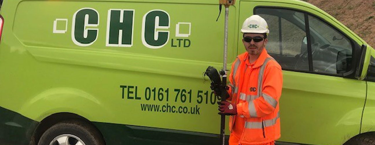 A Bury College student, wearing high visibility workwear, stood infront of a Cheetham Hill Construction van