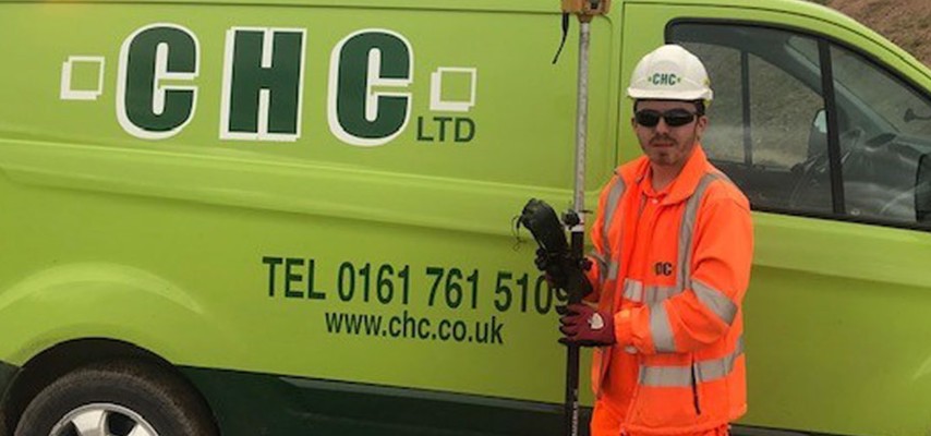 A Bury College student, wearing high visibility workwear, stood infront of a Cheetham Hill Construction van