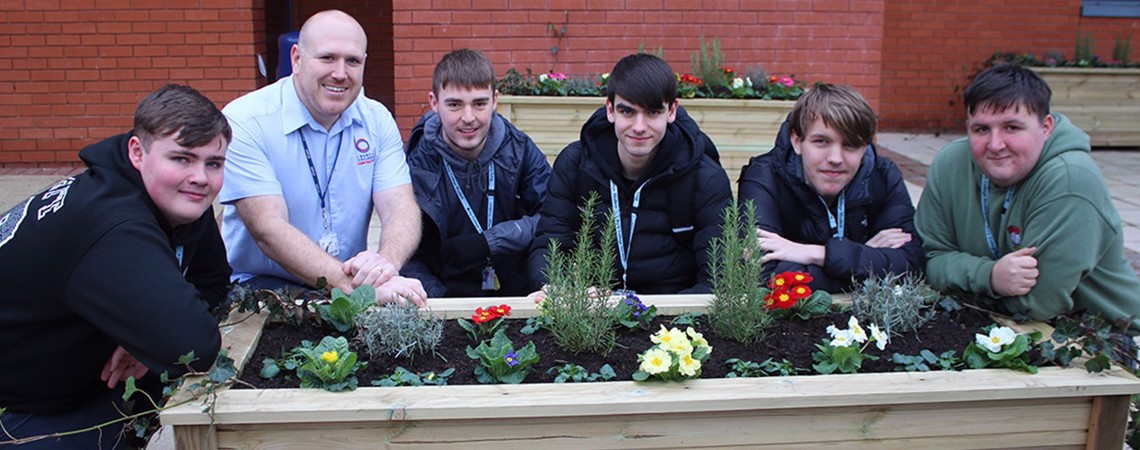 Bury College Carpentry and Joinery students with a handcrafted planter in the courtyard garden