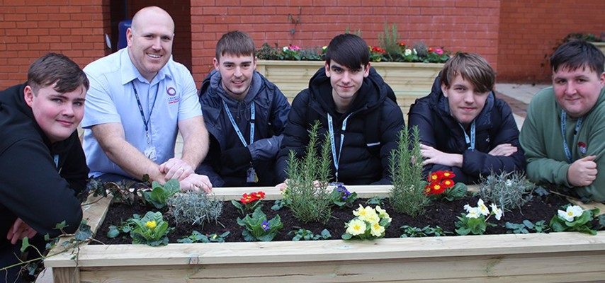 Bury College Carpentry and Joinery students with a handcrafted planter in the courtyard garden