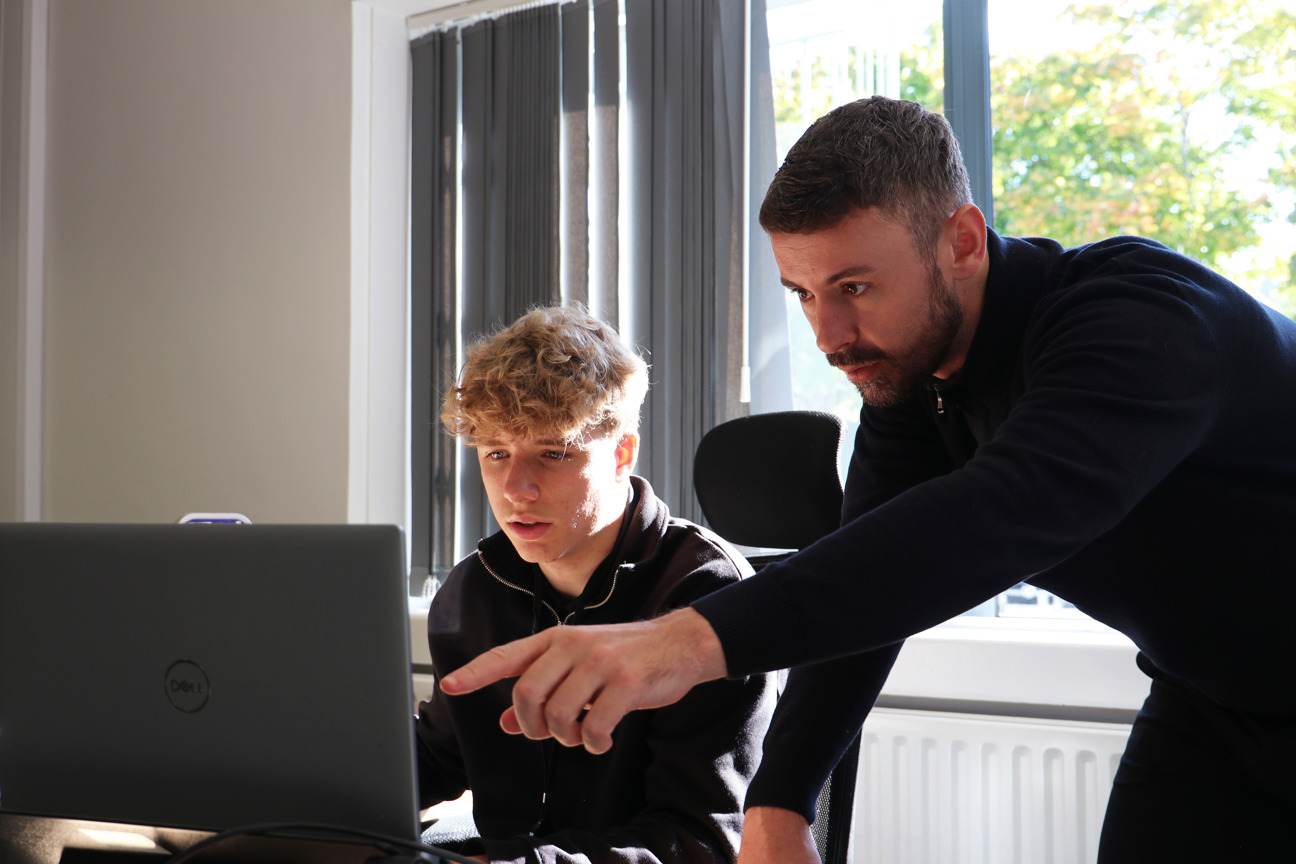 Student Matthew Millward on computer whilst Luke Smith supports