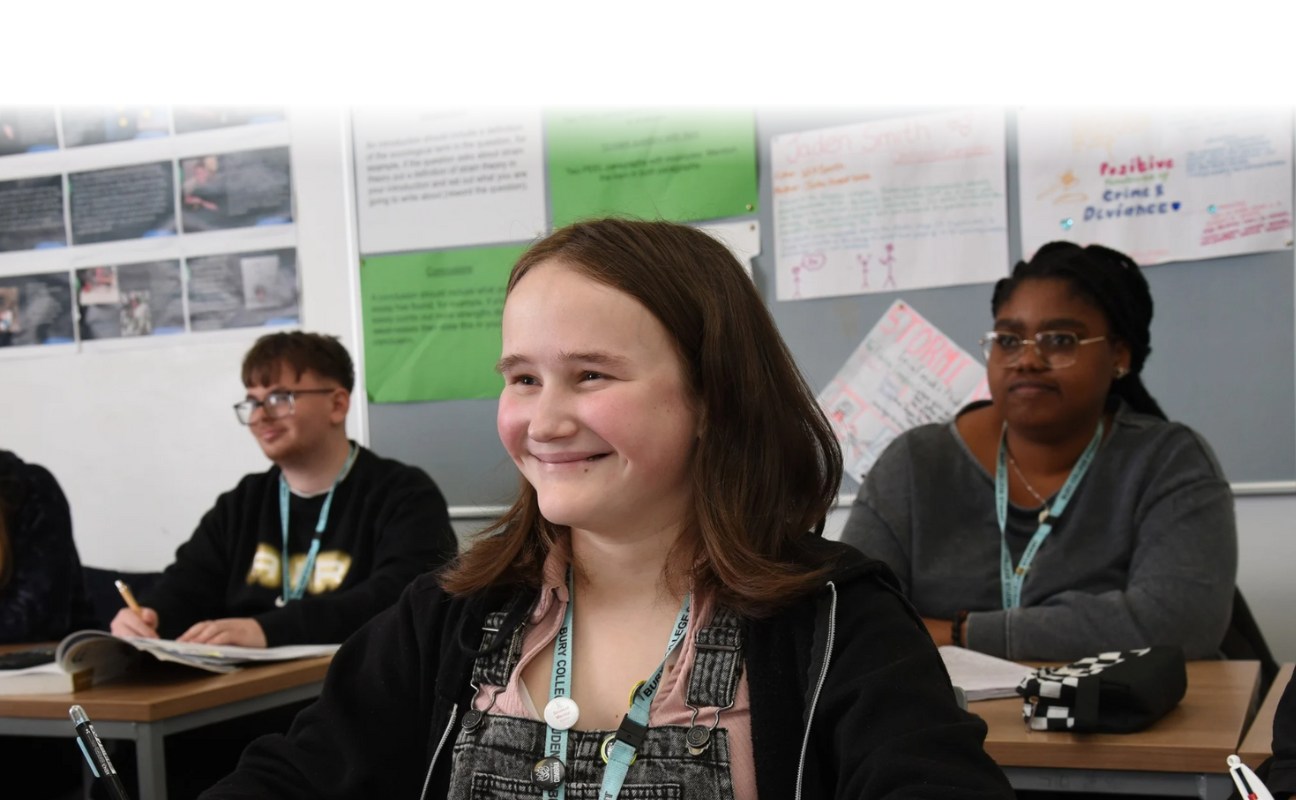 student sat in a classroom smiling