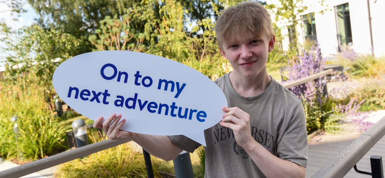 student holding a sign saying on to my next adventure