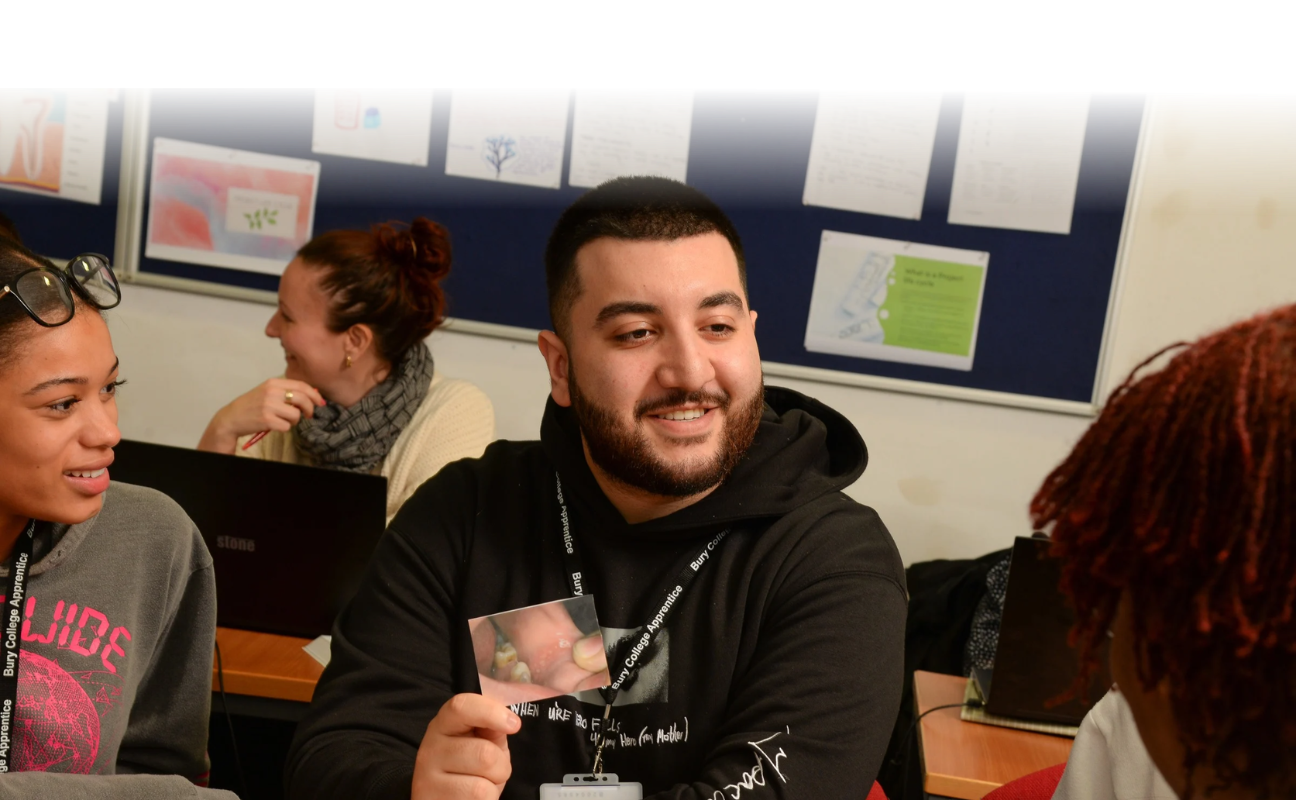 student sat in a dental classroom holding an image of some teeth