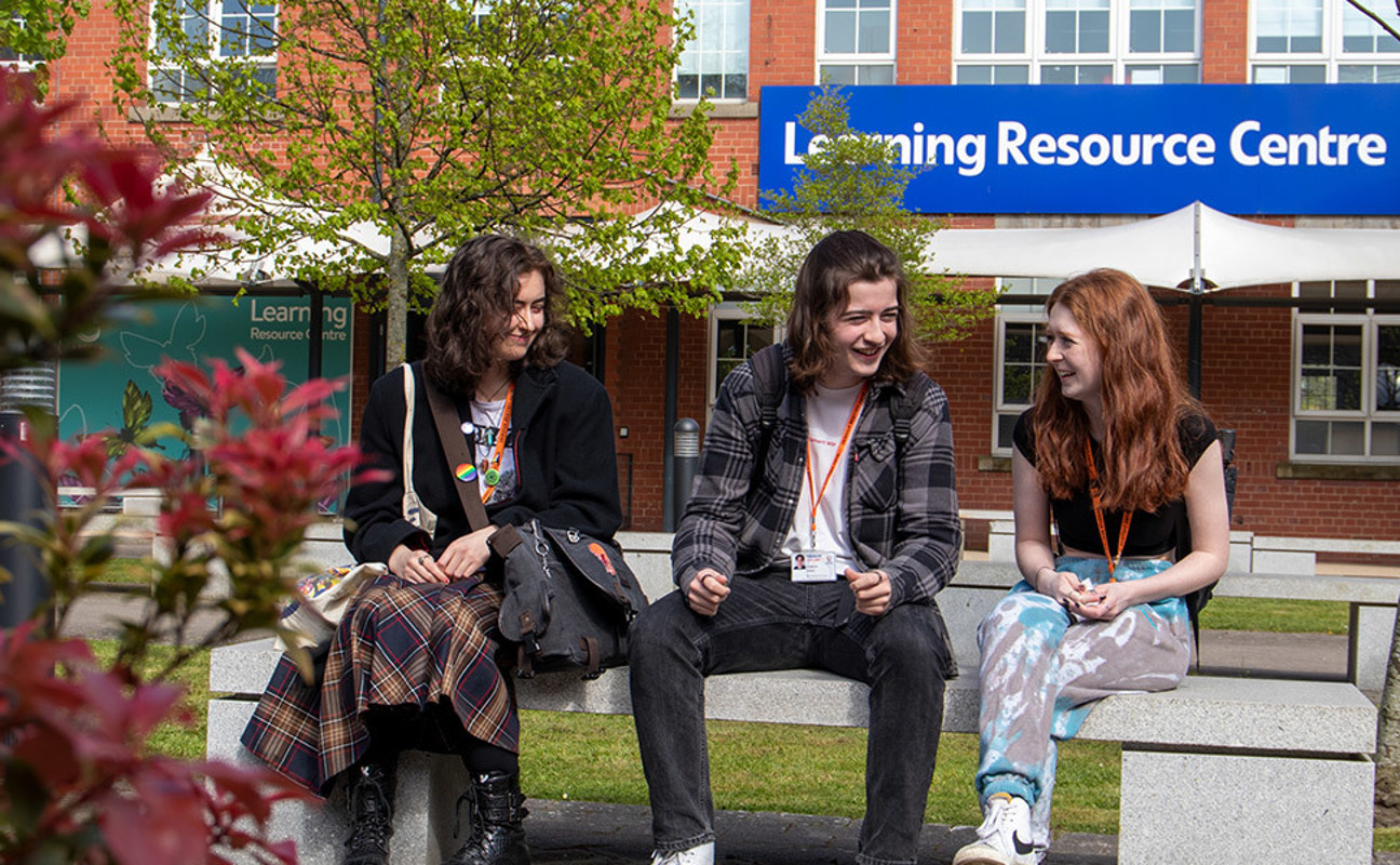 Three students sat outside the Bury College Learning Resource Centre