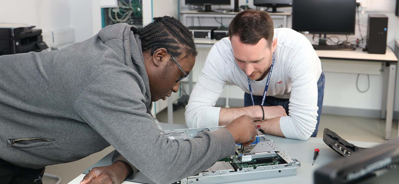 Student building a computer while tutor watches
