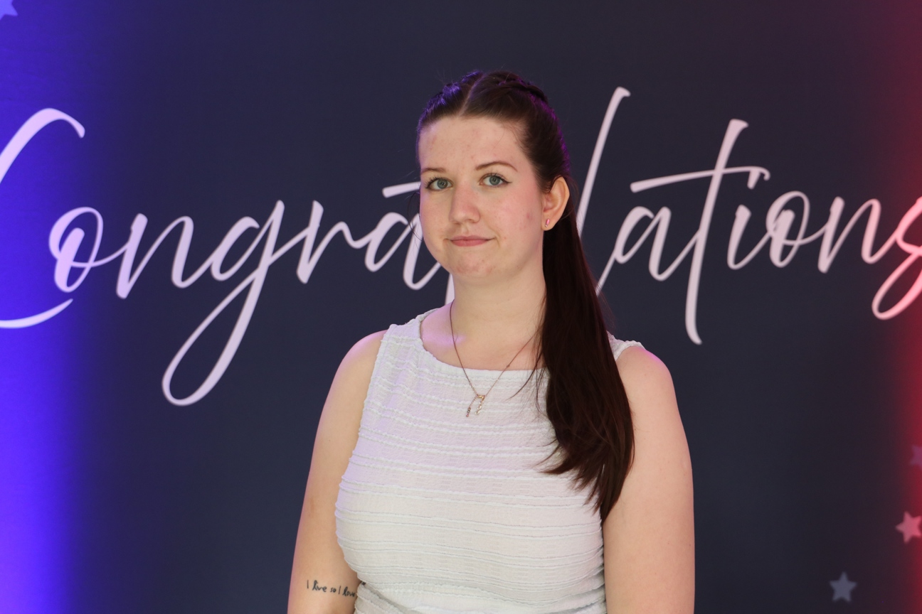 student stood in front of congratulations sign