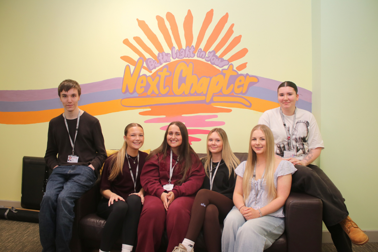 art students sat on a sofa in front of an art mural