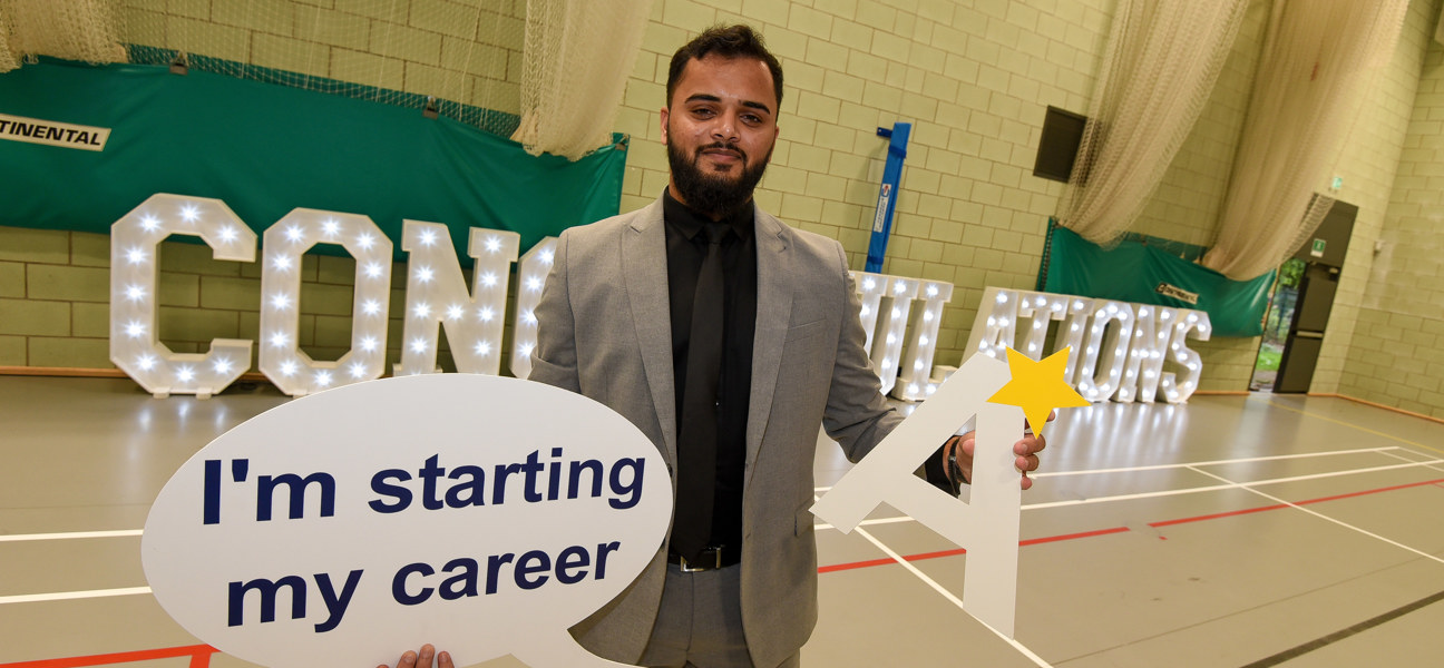 student stood holding career sign in front of congratulations letters